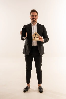 رجل أعمال سعودي يحمل نموذج منزل وهاتف ذكي