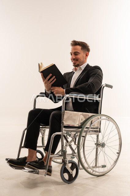 رجل سعودي على كرسي متحرك يقرأ كتاباً في الاستوديو
