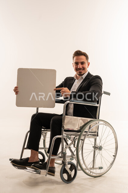 رجل أعمال سعودي على كرسي متحرك يحمل لوحة فارغة