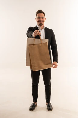 رجل أعمال سعودي يحمل أكياس تسوق ورقية خلفية بيضاء