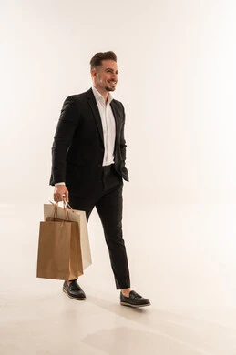 رجل سعودي ببدلة رسمية يمشي مع حقائب تسوق