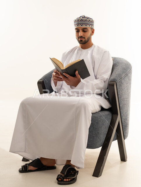 رجل عُماني باللباس التقليدي يقرأ كتاباً