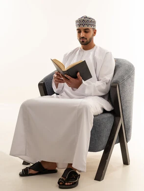 رجل عُماني باللباس التقليدي يقرأ كتاباً