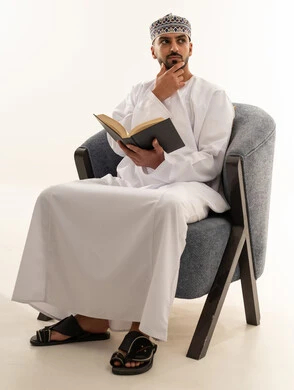 رجل عُماني بالزي التقليدي يقرأ كتاباً