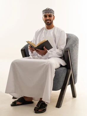 رجل عماني بالزي التقليدي يقرأ كتاباً