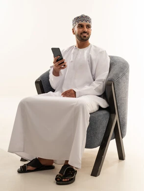 رجل عماني يحمل هاتفاً ذكياً باللباس التقليدي