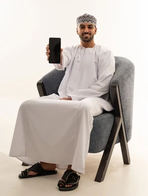رجل عماني بالزي التقليدي يمسك هاتف ذكي