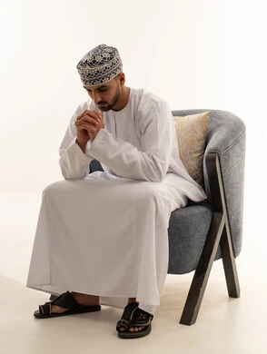 رجل عُماني بالزي التقليدي يجلس على الكرسي