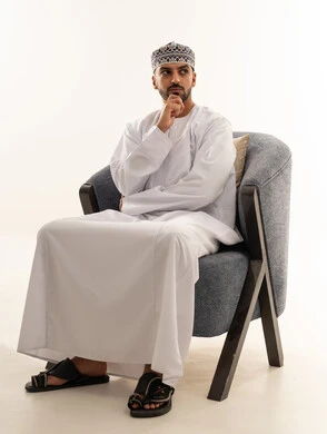 رجل عُماني بالزي التقليدي يفكر على كرسي