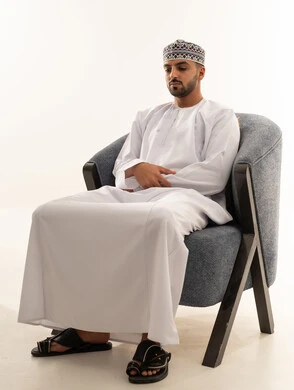 رجل عُماني بالزي التقليدي يجلس على كرسي في استوديو