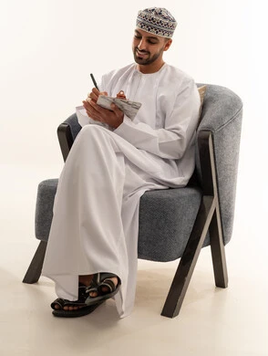 رجل عماني بالزي التقليدي يكتب في دفتر ملاحظات