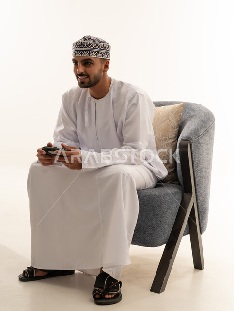 رجل عماني يلعب ألعاب الفيديو بالزي التقليدي