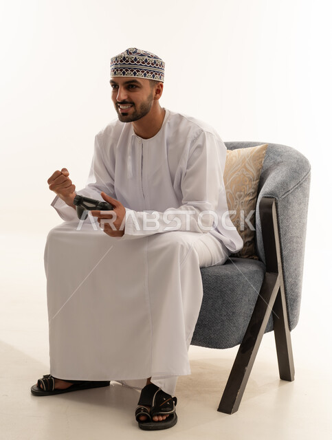 رجل عُماني بالزي التقليدي يلعب ألعاب الفيديو