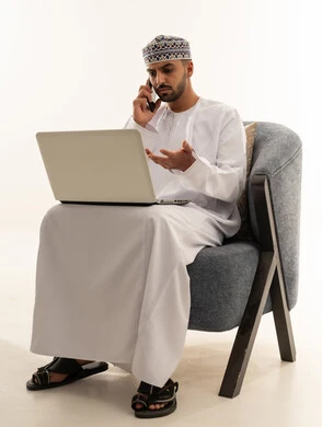 Omani Man with Laptop and Phone in Traditional Dress