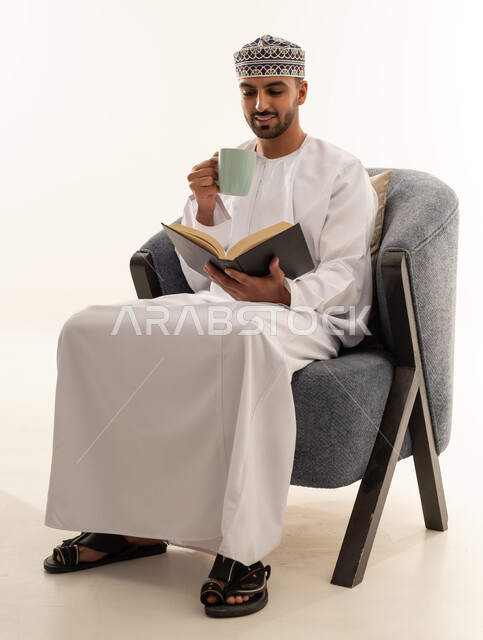 رجل عُماني بالزي التقليدي يقرأ على كرسي