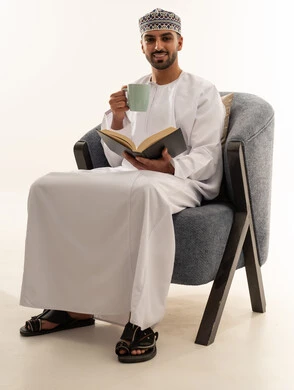 رجل عماني بالزي التقليدي يقرأ كتاباً في الاستوديو