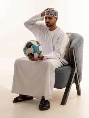 رجل عماني باللباس التقليدي مع كرة قدم