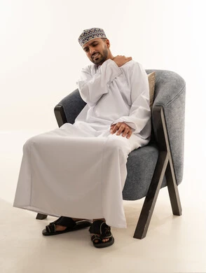 رجل عُماني يعاني من ألم في الكتف بالملابس التقليدية