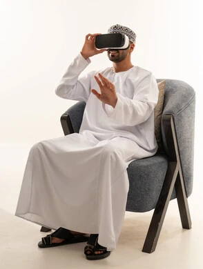 رجل عماني يستخدم سماعة الواقع الافتراضي بالزي التقليدي
