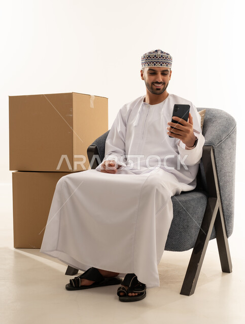 رجل عماني يستخدم الهاتف الذكي بجانب صناديق الشحن