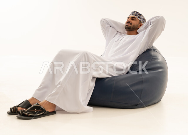Omani Man in Traditional Dress Relaxing on Bean Bag