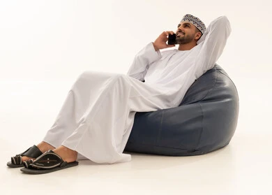 رجل عماني بالزي التقليدي يستخدم الهاتف الذكي