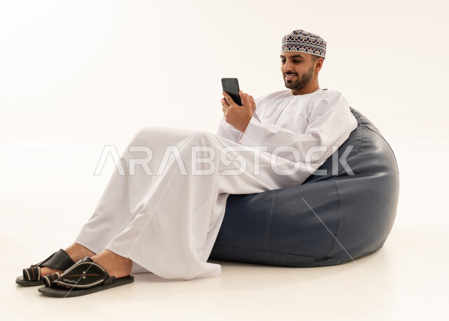 رجل عُماني بالزي التقليدي يستخدم الهاتف الذكي