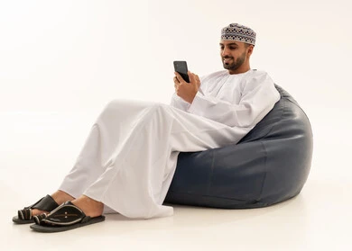 رجل عُماني بالزي التقليدي يستخدم الهاتف الذكي