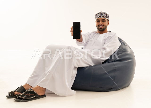 Omani Man with Smartphone on Blue Bean Bag