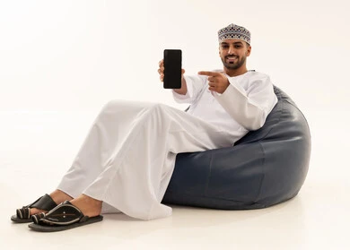 رجل عماني يشير إلى شاشة هاتف ذكي على خلفية بيضاء