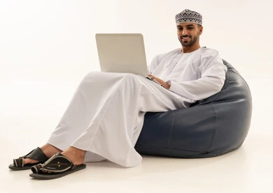 Omani Man Using Laptop on Blue Bean Bag