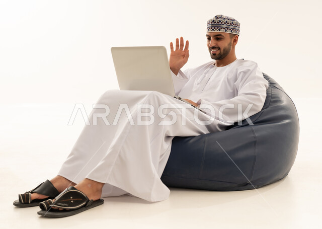 رجل عماني بالزي التقليدي يجري مكالمة فيديو باللابتوب