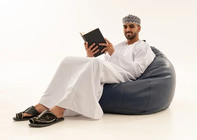 Omani Man in Traditional Dishdasha Reading on Bean Bag