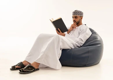 رجل عماني يقرأ كتاب بالزي التقليدي