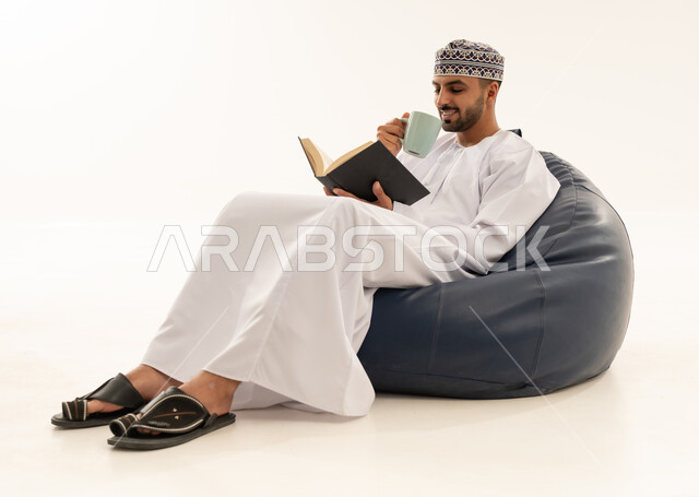 رجل عماني بالزي التقليدي يقرأ على مقعد محشو