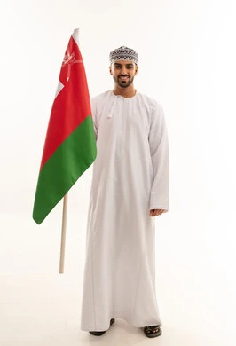 رجل عماني بالزي التقليدي يحمل علم سلطنة عمان