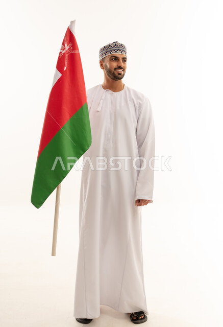 رجل عماني بالزي التقليدي يحمل علم سلطنة عمان