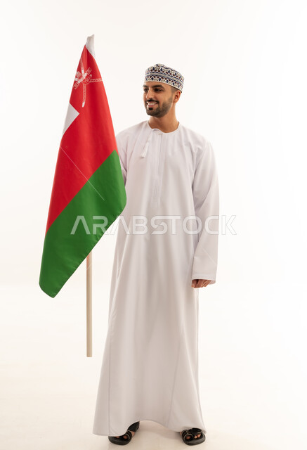 رجل عماني بالزي التقليدي يحمل علم سلطنة عمان