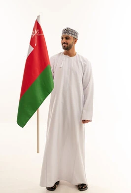 رجل عماني بالزي التقليدي يحمل علم سلطنة عمان