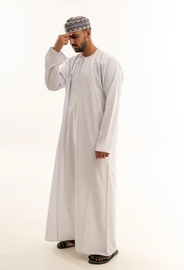 رجل عُماني بالدشداشة التقليدية يفكر أمام خلفية بيضاء