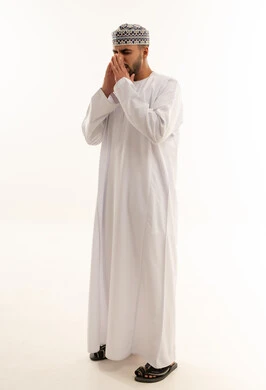 رجل عماني بالزي التقليدي يدعو أمام خلفية بيضاء