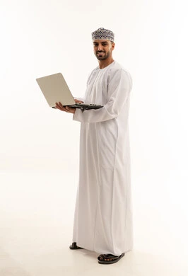 رجل عُماني بالزي التقليدي يحمل جهاز كمبيوتر محمول في استوديو