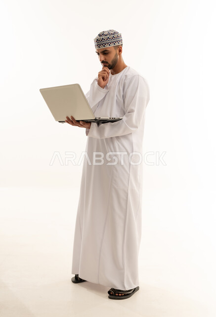 رجل عماني بالزي التقليدي يستخدم الحاسوب المحمول