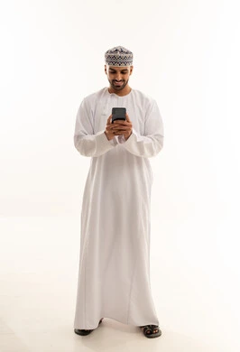 رجل عماني بالزي التقليدي يستخدم الهاتف الذكي