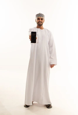 رجل عماني بالزي التقليدي يمسك هاتف ذكي