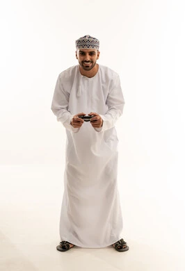 رجل عماني يلعب بجهاز تحكم على خلفية بيضاء