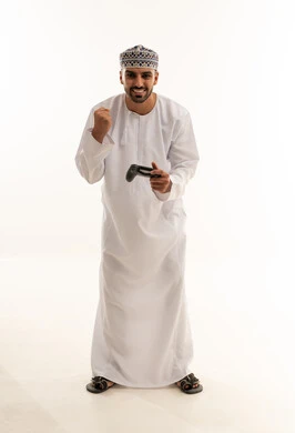 رجل عماني بالزي التقليدي يلعب ألعاب الفيديو
