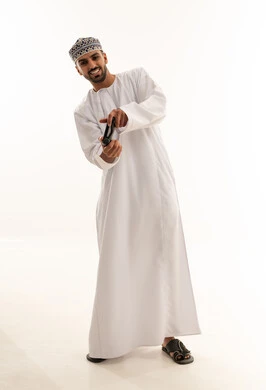 رجل عماني بالزي التقليدي يلعب ألعاب الفيديو