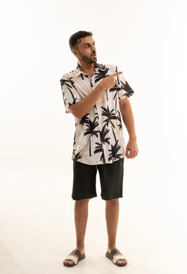 رجل عربي بملابس صيفية يشير أمام خلفية بيضاء