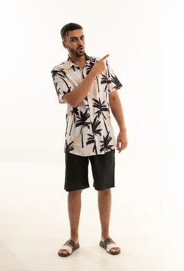 رجل سعودي بملابس صيفية يشير على خلفية بيضاء